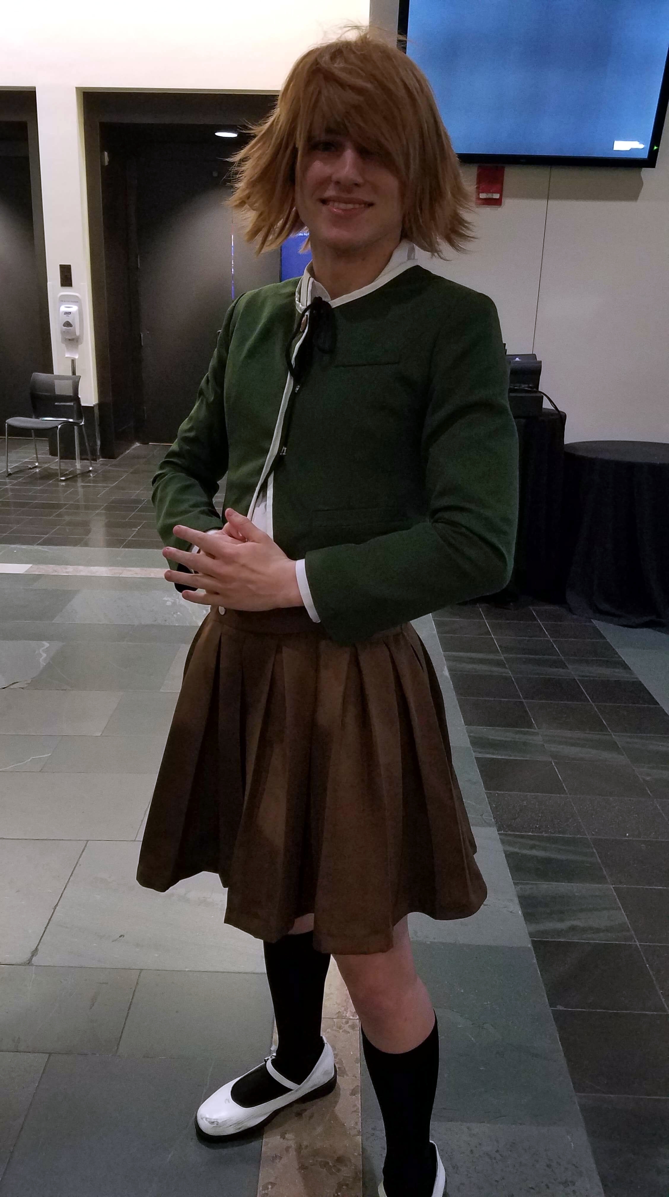 A cosplayer cosplaying Chihiro Fujisaki in front of a pair of elevators.